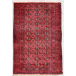 A Persian Balouch rug with repeat design on a red ground, 202 by 115cms.