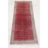 A Persian Turkoman hand knotted woollen runner with repeated rows of guls within geometric