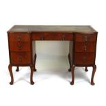 A walnut kneehole desk, the top with inset green leather above an arrangement of seven drawers, on