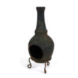 A cast iron miniature chimenea on a wrought iron tripod stand, 43cms high.