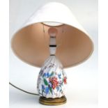 A continental pottery table lamp decorated with flowers on a gilt metal base, 23cms high.