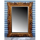 A Florentine style carved wood mirror with bevel edged rectangular plate, 118cms wide.