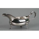 An 18th century Irish provincial silver sauce boat of oval form with scroll handle, on three shell