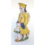 A faience pottery character jug in the form of a gentleman seated on a barrel wearing a yellow