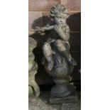A well weathered reconstituted stone figure of a cherub playing a flute, seated on a column,
