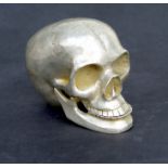 A silver plated desk top skull paperweight with articulated lower jaw, 9cms high.
