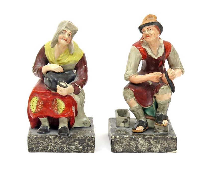 A pair of Staffordshire pearlware figures of the Cobbler and his wife c.1820, both seated, she