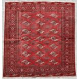 A Persian Turkoman rug with repeated guls within a stylised border, on a red ground, 155 by