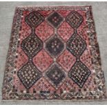 A Persian Shiraz rug decorated with a geometric design on a red ground, 190 by 157cms.