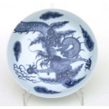 A Chinese blue & white shallow dish decorated with a dragon amongst clouds, 22cms diameter.