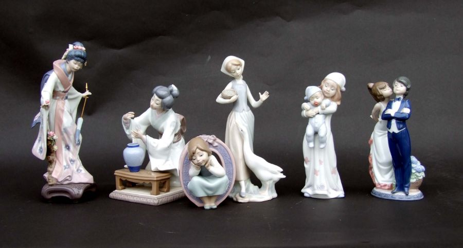 A group of Lladro figures to include a girl feeding a goose, a girl holding a baby and two