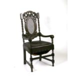 A 17th century style oak carver chair with carved and cane back panel, leather overstuffed seat,