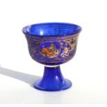 A Venetian blue glass footed bowl decorated with classical figures within ovals and gilded winged