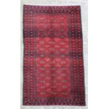 A Persian Balouch hand knotted woollen rug with repeated guls within borders on a red ground, 205 by