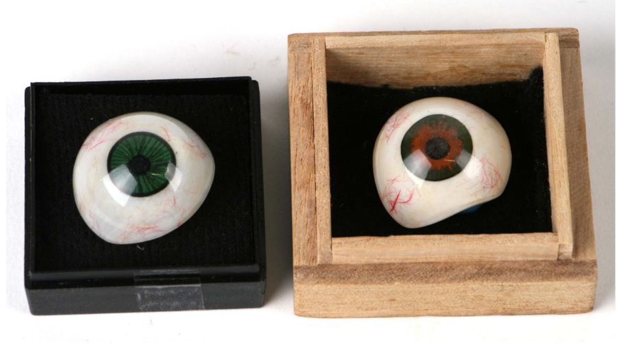 Two prosthetic glass eyes, one with a brown iris, the other with a green iris (2).