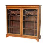 An Edwardian inlaid mahogany two-door bookcase with shelved interior, on bracket feet, 124cms wide.