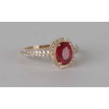A 14ct gold diamond and ruby ring, the central oval ruby surrounded by diamonds and having diamond