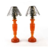 A pair of mid century phenolic amber / Catalin table lamps with pierced chrome plated shades,