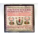 An early 20th century French needlework sampler with alphabet, numbers, cottages and crucifix within