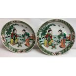 A pair of Chinese plates, each decorated with two seated females and a boy playing, 24.5cm diameter