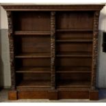 A 20th century oak open bookcase, heavily carved with lion masks, fruit, fauna and maidens, with