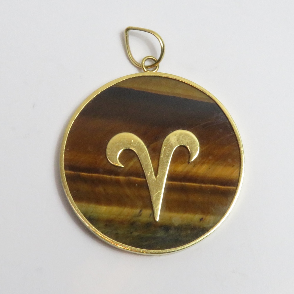 An Aries the Ram tiger eye pendant, the applied symbol for Aries to a frame tagged '750' to the