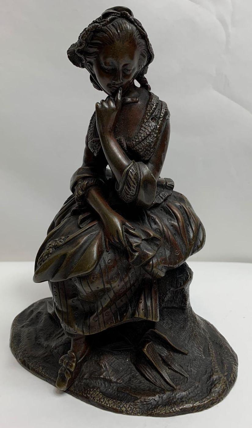 A 20th century bronze figure of a girl seated on a rocky base, 16cm high