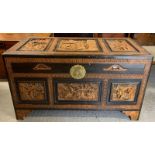 A heavily carved two-tone camphorwood chest on four bracket feet with decorative brass lock, 104cm