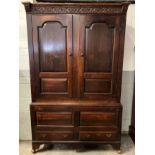 An 18th century and later stained oak double wardrobe, the top with a carved frieze, with two