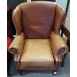 A light brown leather wing back armchair, with nail head decoration, on block and turned legs