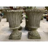 A pair of reconstituted stone planters of tall tru