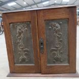An art nouveau oak smokers cabinet, the doors deco