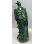 A heavy glazed pottery figure of a peacock perched