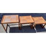 A nest of three teak and tile top tables, the larg