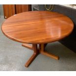 An extending teak wood dining table, the circular