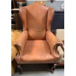 A Georgian style wing back armchair upholstered in