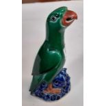 A glazed pottery figure of a parrot perched on a r