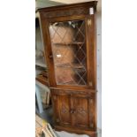 Stained oak corner cupboard with glazed door to th
