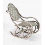 A miniature rocking chair in unmarked white metal,