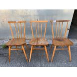 Three Ercol beech dining chairs, each with stick b