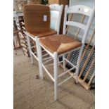 2 white painted bar stools with wicker seats along