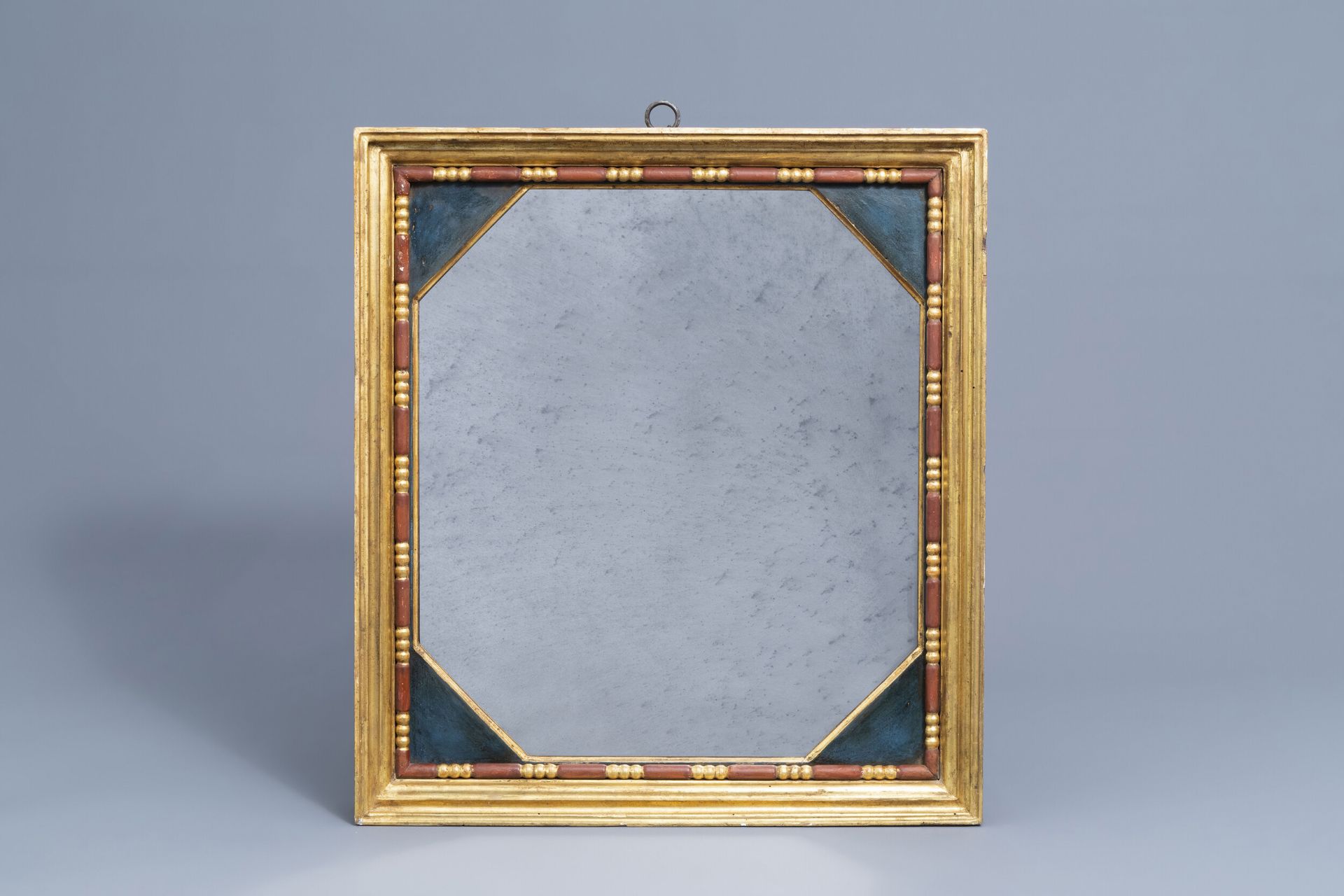 An octagonal mirror in a gilt and polychrome decorated wooden frame, 20th C.