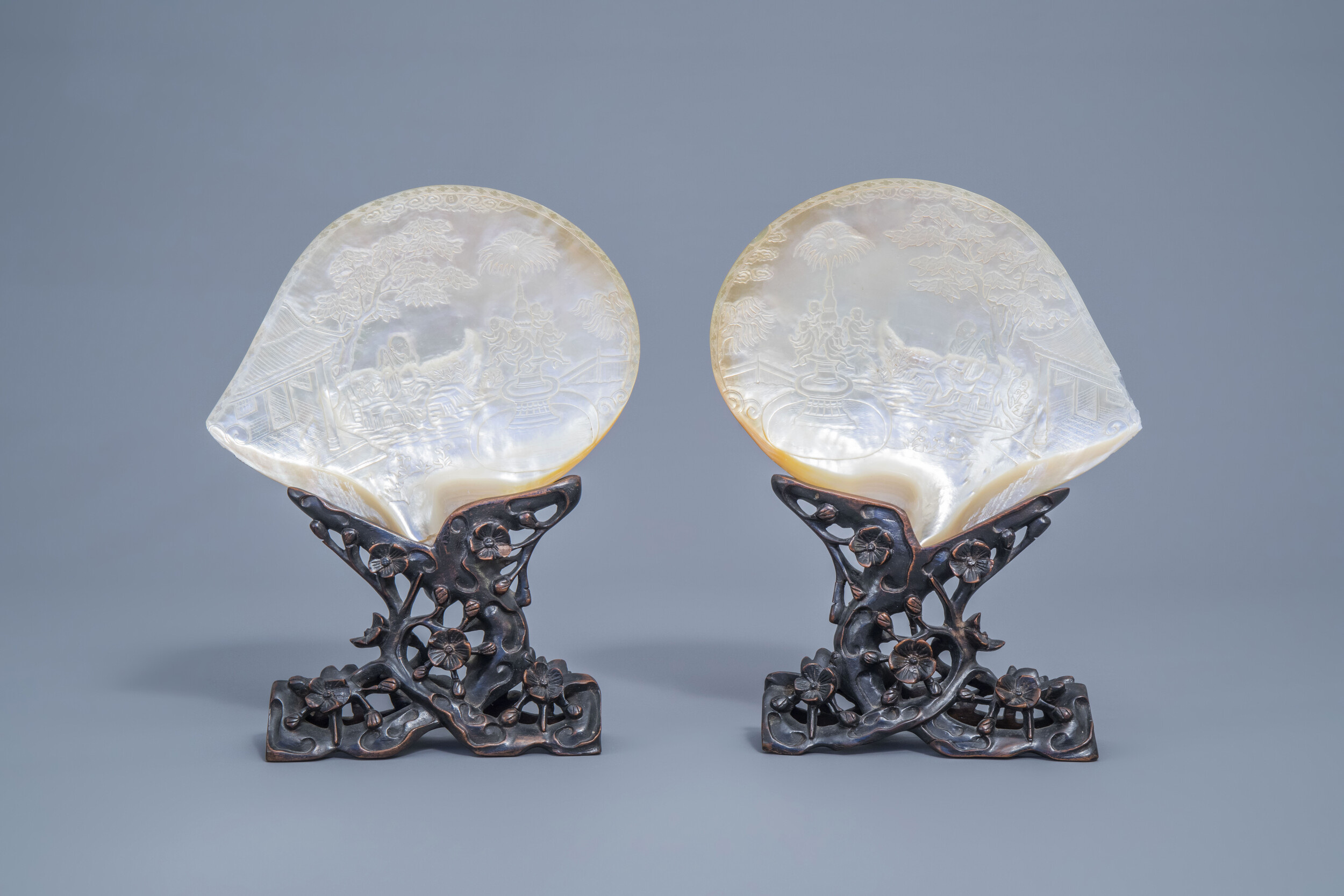 A pair of Chinese carved mother-of-pearl shells on wooden stands, 19th C.