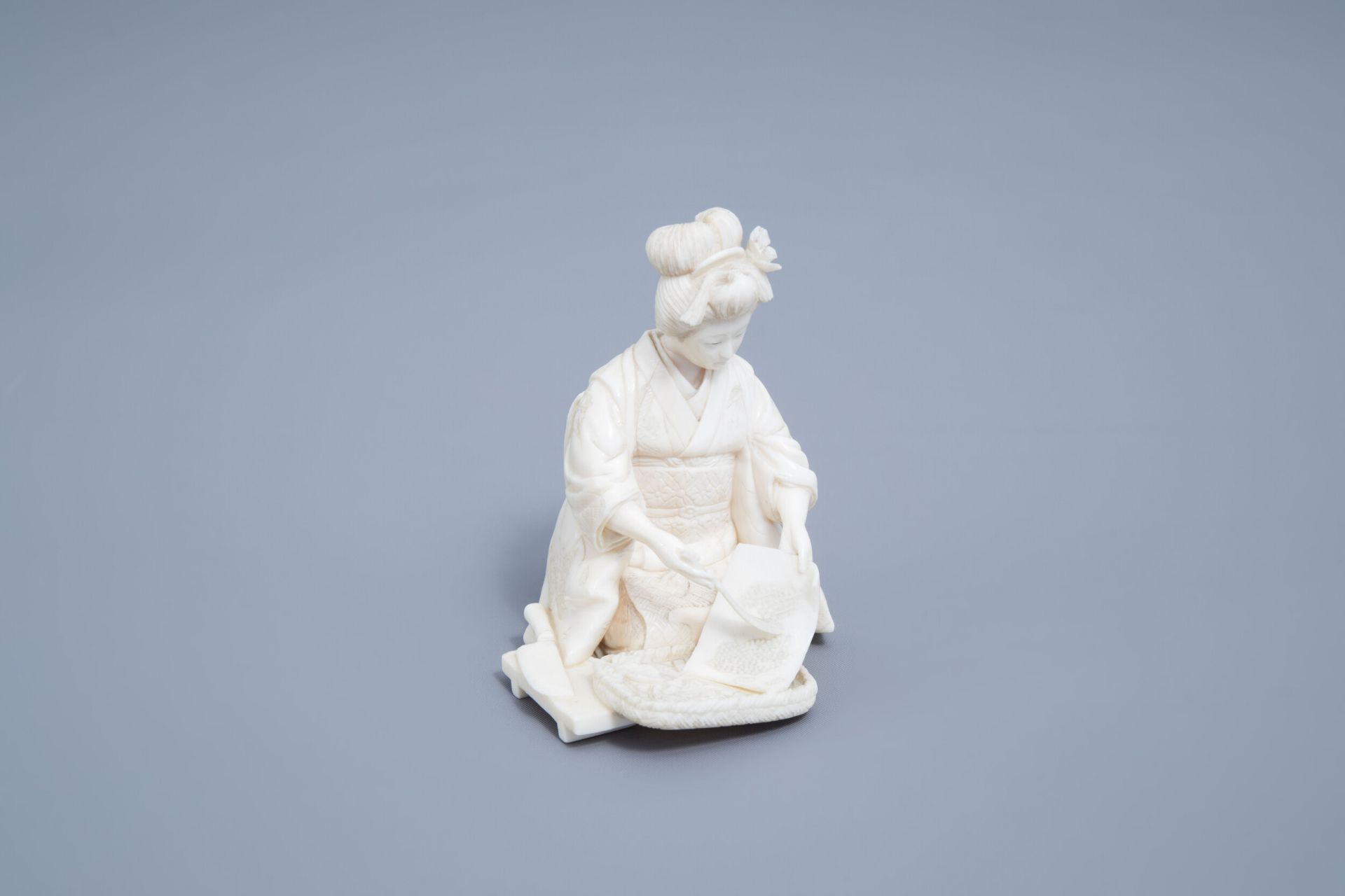 A signed Japanese ivory ikomono of a lady at work, Meiji, 19th/20th C.