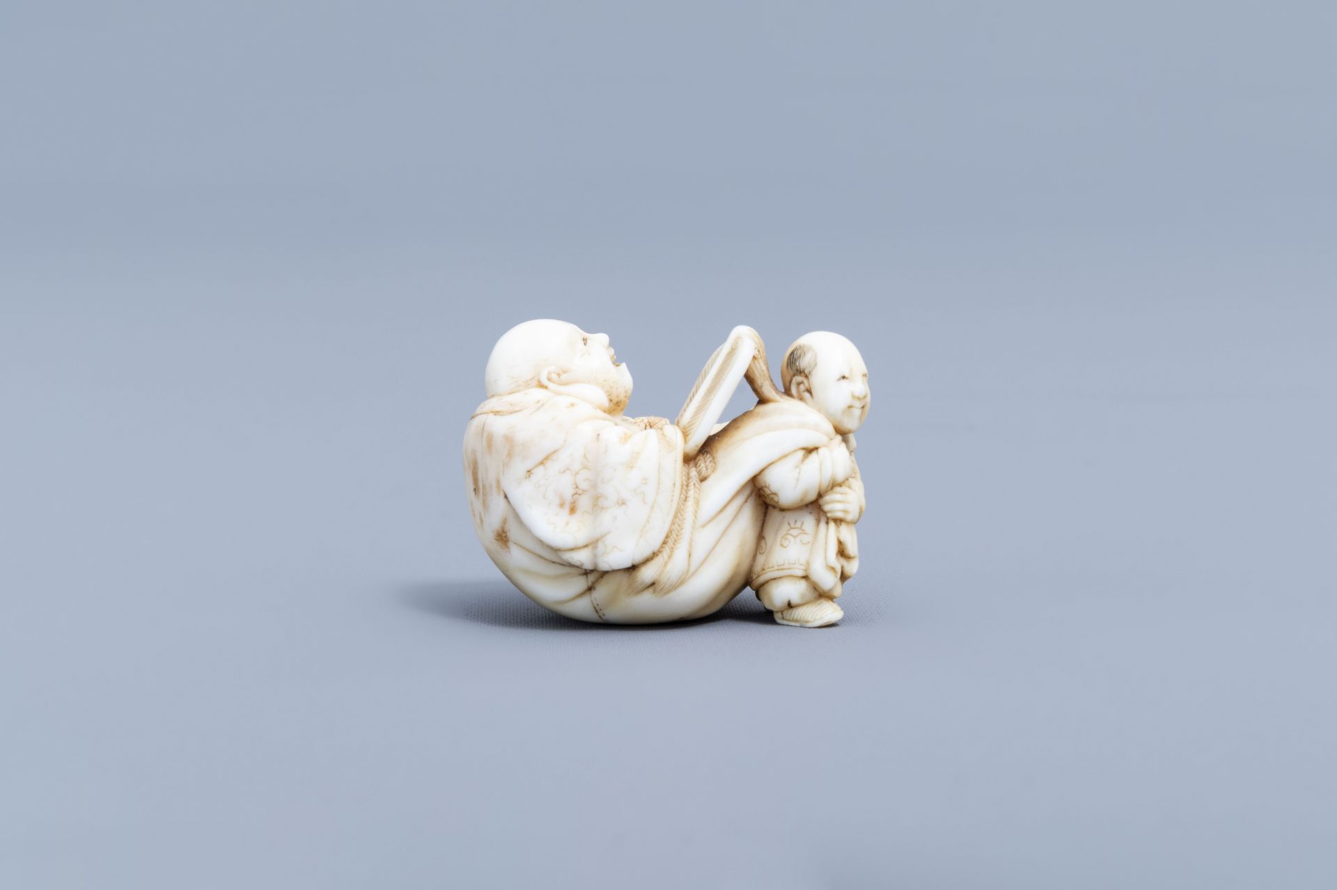 A Japanese ivory netsuke of a laughing Buddha with his servant, signed Shinsai, Edo - Image 3 of 9