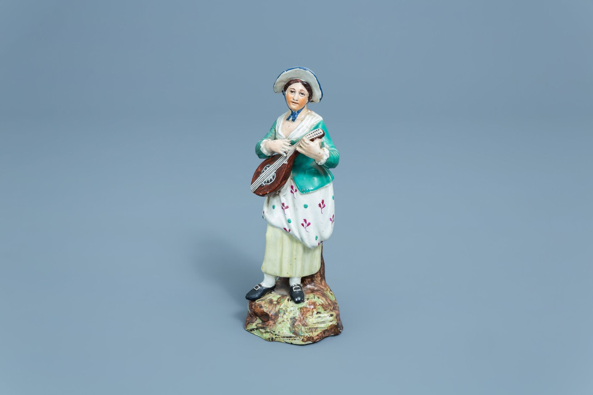 A German polychrome decorated earthenware figure of a lady with a mandolin, Hšchst, 18th C.