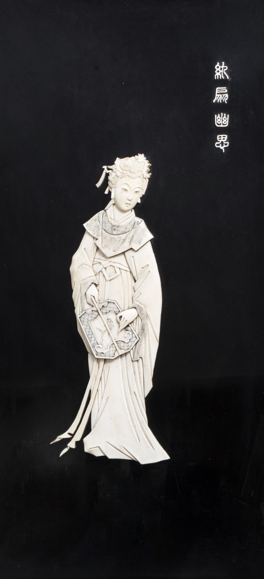 A Chinese ivory carving of a lady with a fan mounted on a plaque, first half of the 20th C.