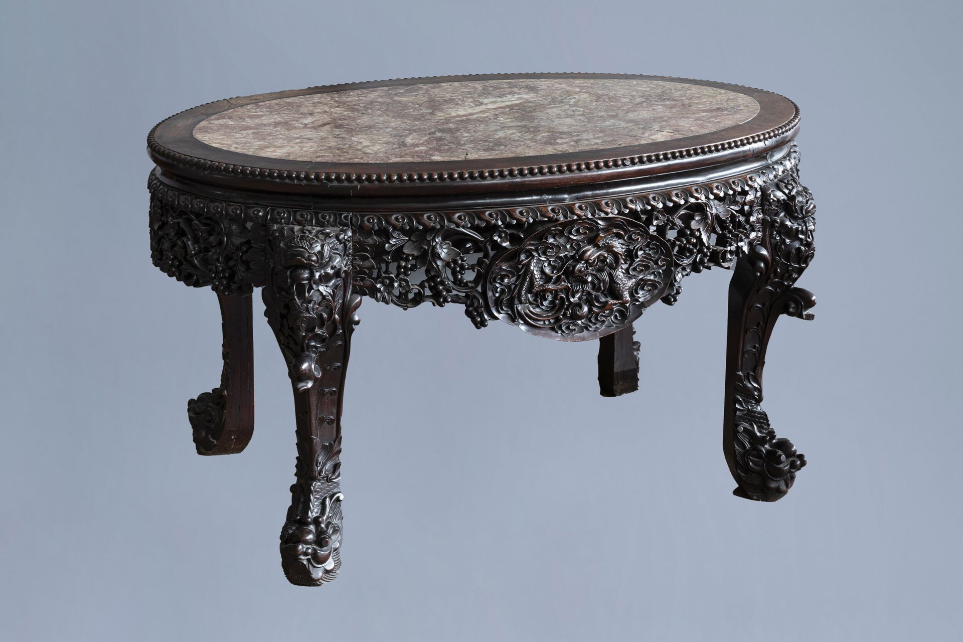 An oval Chinese finely carved wooden table with marble top, 19th C.