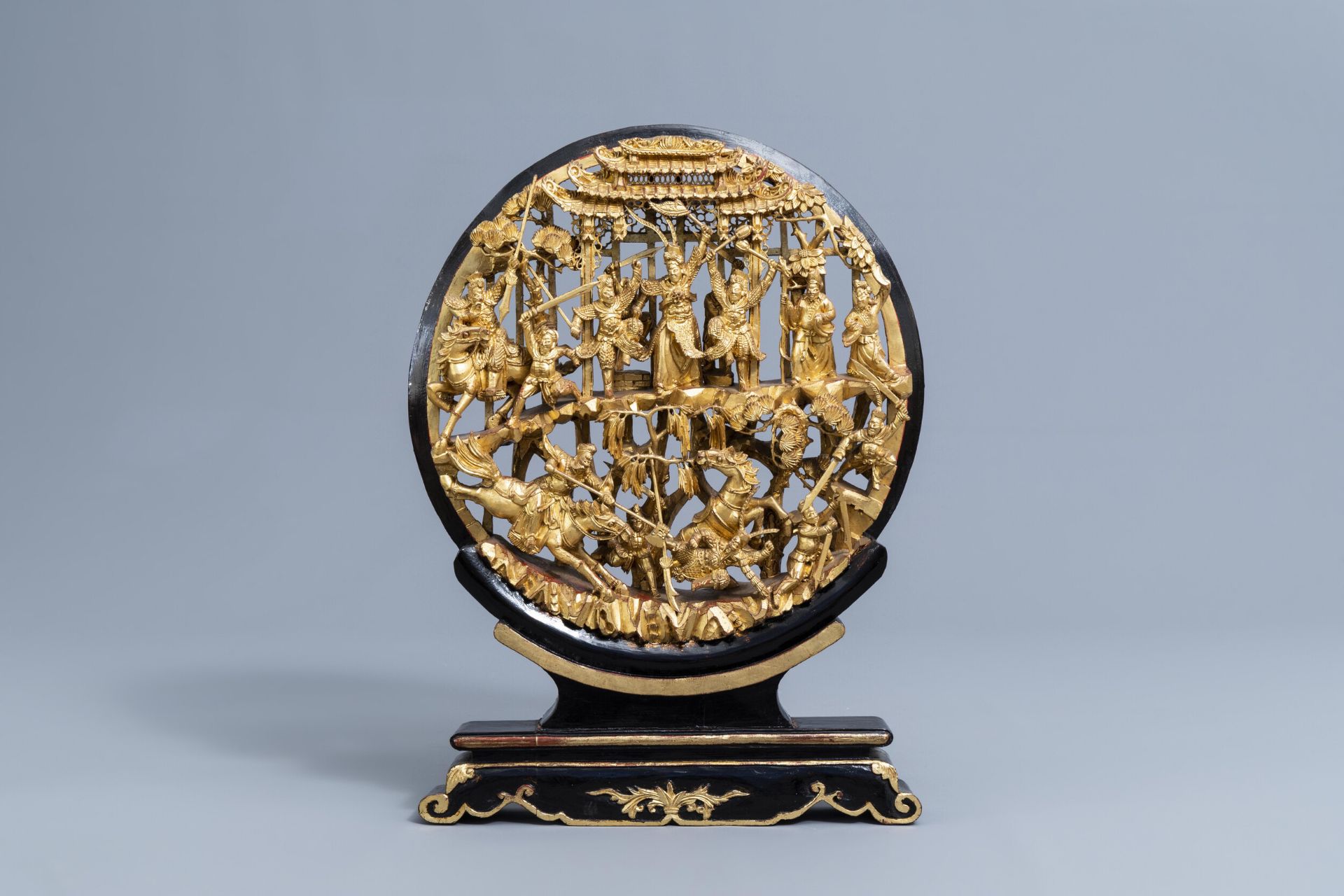 A Chinese reticulated gilt wood 'battle scene' medallion on stand, 19th C.