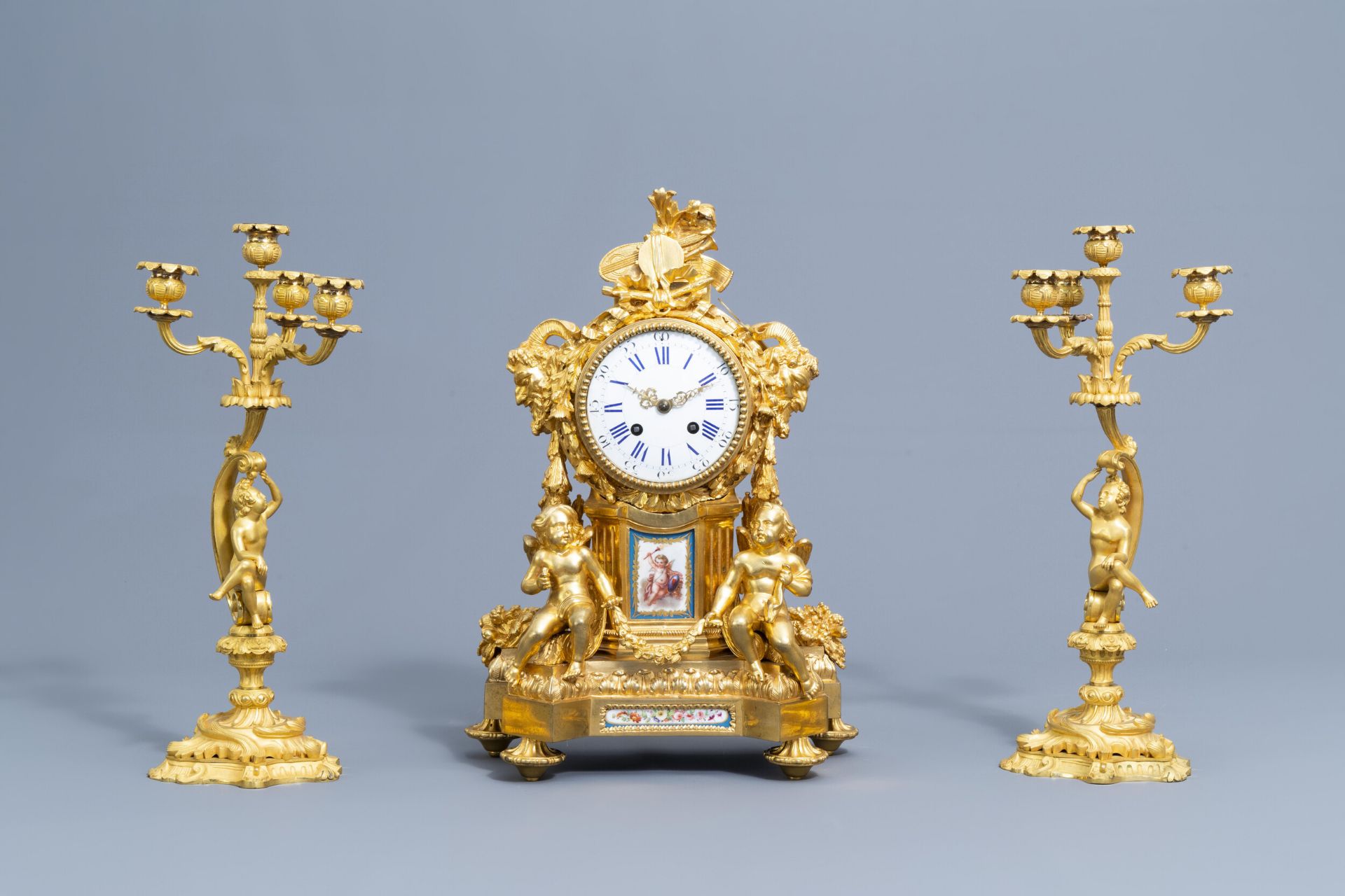 A French gilt bronze mounted Sevres style clock and a pair of Louis XV style candelabra, 19th C.